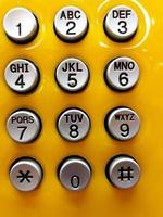 Gray or grey phone numbering keypad for press to call on yellow background. photo