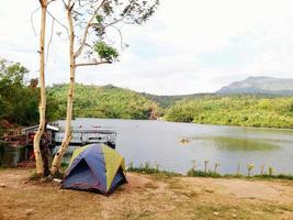 Camping time on long holiday or vacation. Tent staying on the ground beside tree with lake and mountain view at Wang Bon Reservoir, Nakhon Nayok, Thailand photo