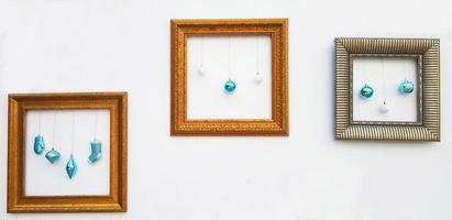 Yellow or Golden, brown picture frame mockup with blue ball and light bulb hanging on white concrete wall with copy space. Framework on background. Decorate for festival, Celebrate party. photo