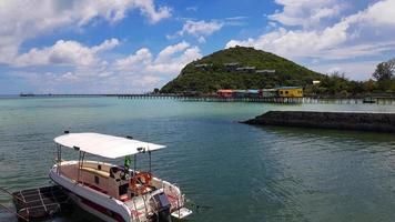 Speedboat or boat parked and waiting for group of the tour, people or tourist to taking for trip on sea or ocean with blue sky, white cloud, colorful resort and green mountain background. Beauty view photo