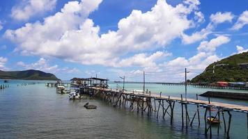 Wooden bridge pathway for group of people, tour, tourist walk to get in speedboat and longtail boat to take trip on sea go to island and fishing fish and squid with white clouds, blue sky background. photo