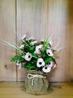 Beautiful flower bouquet in weave bag on shelf with wooden background. photo