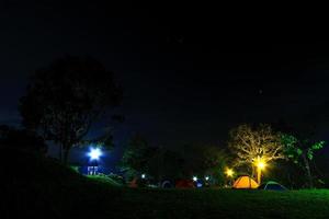 Camping tent with light in grass field at night. Activity photo