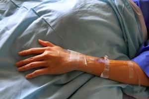 Patient's hands giving the saline solution on bed with copy space. Healthy, Medicine or Medical and injection. People cure sickness and fever at hospital or clinic concept. photo