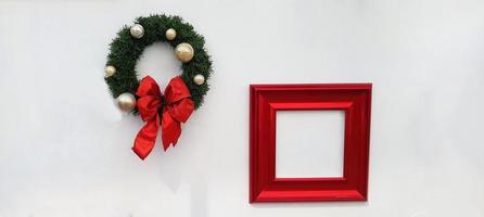 Christmas, happy new year wreath decoration with red ribbon, white ball and red picture frame for add wording isolated on white wall background. Object for decorated party, festival with copy space. photo