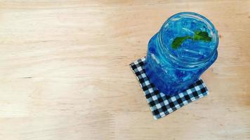 Fresh Blue Hawaii soda with mint leaves on the wooden table and left copy space. Top view of cocktail drink. photo