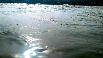 Water surface with ripples and sunrays reflections in ganga river at rishikesh photo