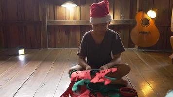 en pojke i en tomteluva sitter ensam hemma och öppnar en presentförpackning på juldagen. video