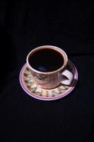 a glass containing brewed black coffee on a black background photo