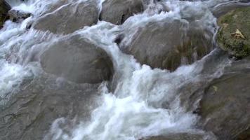 de stroom stroomt door de rotsen en rotsen in de stroom. video