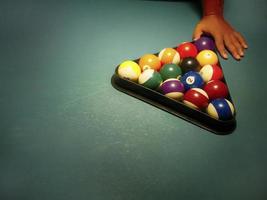 Hand preparing pool balls in triangle rack on the billiard table with copy space photo