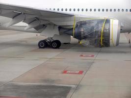 An aerplane parking for repair on the airfield, plastic wrap with yellow tape at jet engine, airplane mechanic part photo
