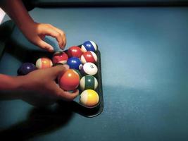 Hands  preparing pool balls in triangle rack on the  billiard table photo