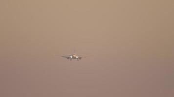 beelden van een straalvliegtuig dat bij zonsopgang afdaalt om te landen. onherkenbaar passagiersvliegtuig vliegt, vooraanzicht video