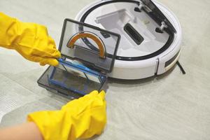 Robot vacuum cleaner, taking out filter, cleaning. Close up. photo