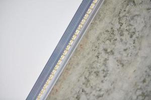 Strip LED light with aluminum profile on stretch ceiling, close up. Home renovation concept photo