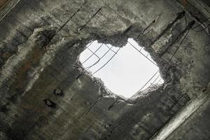 Vintage abandoned damaged house roof with hole in ceiling overlooking cloudy sky photo