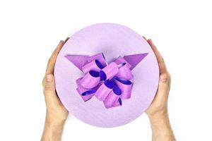 Round gift box with bow in hands, isolated photo