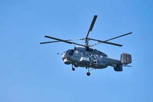 Navy helicopter flying against blue sky background, copy space. One rotary wing aircraft, side view photo