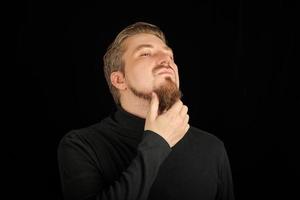 Thoughtful bearded man, half profile portrait, black background photo