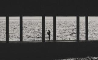 Silhouette of fisherman with fishing rod on pier photo