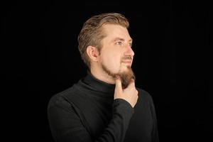 Thoughtful bearded man, half profile portrait, black background photo