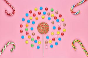 Sweet lollipops and candy canes on pink background photo