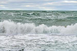 Blue sea with foaming waves and cloudy sky, seascape photo