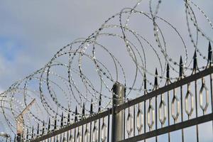 Barbed wire on fence, steel grating fence with barbs photo