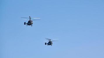 Two military helicopters flying in bright blue sky performing demonstration flight, aerobatic team photo