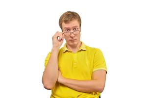 Young surprised man looking over his glasses, man in yellow T-shirt isolated on white background photo