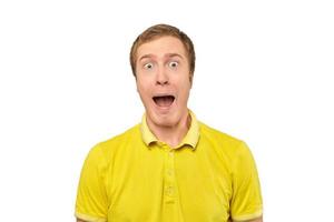 Surprised young man with funny facial expression in yellow T-shirt, white isolated background photo