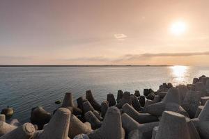 Tetrapod breakwaters in sea water. Beautiful sunset seascape with concrete tetrapodes for protect coastal structures from storm sea waves, effects of weather and longshore drift photo