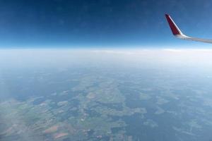 Airplane window view to cloudy sky and earth. Beautiful landscape from aircraft cabin. Flying without fear of flying, incidents and turbulence. photo