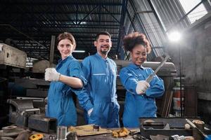 los trabajadores de la industria multirracial con uniformes de seguridad colaboran con unidad, actúan con herramientas y expresan un trabajo feliz junto con una sonrisa y alegría en la fábrica mecánica, ocupación de ingenieros profesionales. foto