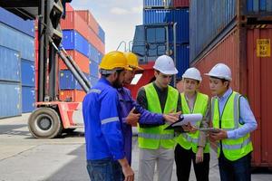 A Group of multiracial workers people in safety uniforms and hardhats work at logistics terminal with many stacks of containers, loading control shipping goods for the cargo transportation industry. photo