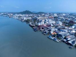 Fishing boats in a fishing village reflecting on the water. Life of a fishing village in shore of Songkhla, Thailand from drone bird eye view. photo