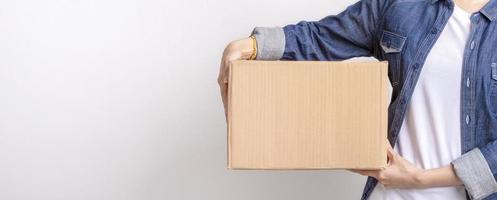 Asian delivering package with brown box isolated on grey background , Closeup hands of delivery holding package to deliver photo