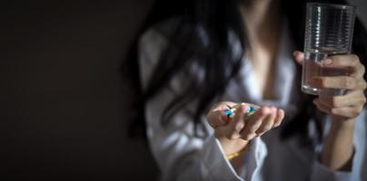 Close up Asian woman holding pill capsule and a glass of water in young female hand photo