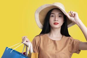 retrato de una mujer asiática que lleva bolsas de compras coloridas en un fondo azul aislado, concepto de venta de verano, una mujer joven disfruta feliz con las compras foto