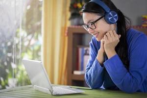 Happy young asian woman online using laptop while connection on video conference at home , Asia girl speaking looking at camera talking with video conference photo