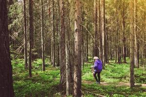 Side view woman on road walk with nordic sticks in forest surrounded with trees. Texture and nature well-being concept background photo