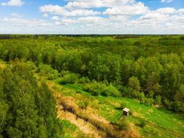Wide aerial view wooden hunting tower in sunny day. Aerial view from above big fields of farm land and one lonely wooden hunting tower photo