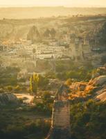 Golden sunrise over Goreme town in Cappaocia front side sunlight directional with balloons on air in sunny hazy autumn calm morning photo