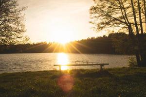 Panoramic view of calm Pageluvis lake during sunset with couple standing in front. Pristine nature and lakes in Lithuania countryside photo