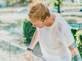 retrato de hombre caucásico sacudiendo la cabeza con salpicaduras de agua. diversión de verano, fiesta, vacaciones, emociones, placer, relajación, concepto de refresco foto