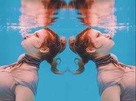 surreal art portrait of young woman in grey dress and beaded scarf underwater in the swimming pool