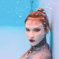 surreal art portrait of young woman in grey dress and beaded scarf underwater in the swimming pool photo