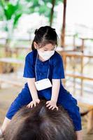 Portrait image child 5 year old. Cute Asian girl is riding on back of black buffalo. Children get close to farm animals. Learning rural lifestyle. Lessons outside classroom. Kid wear blue farmer dress photo