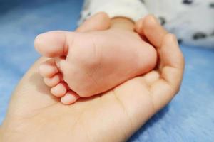 padre sosteniendo en las manos los pies del bebé recién nacido. la mano de la madre cubriendo los pies de su bebé. foto